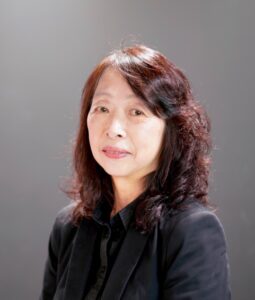 草原真知子さんの写真。髪が肩まであり、黒いシャツを着ている。