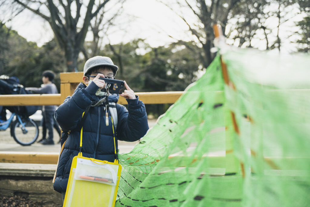 ワークショップ参考イメージ。街中でなにかを発見し、撮影している子供の様子