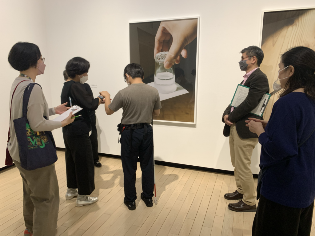写真作品の前に立ち、触手話で作品の描写を聞く森氏