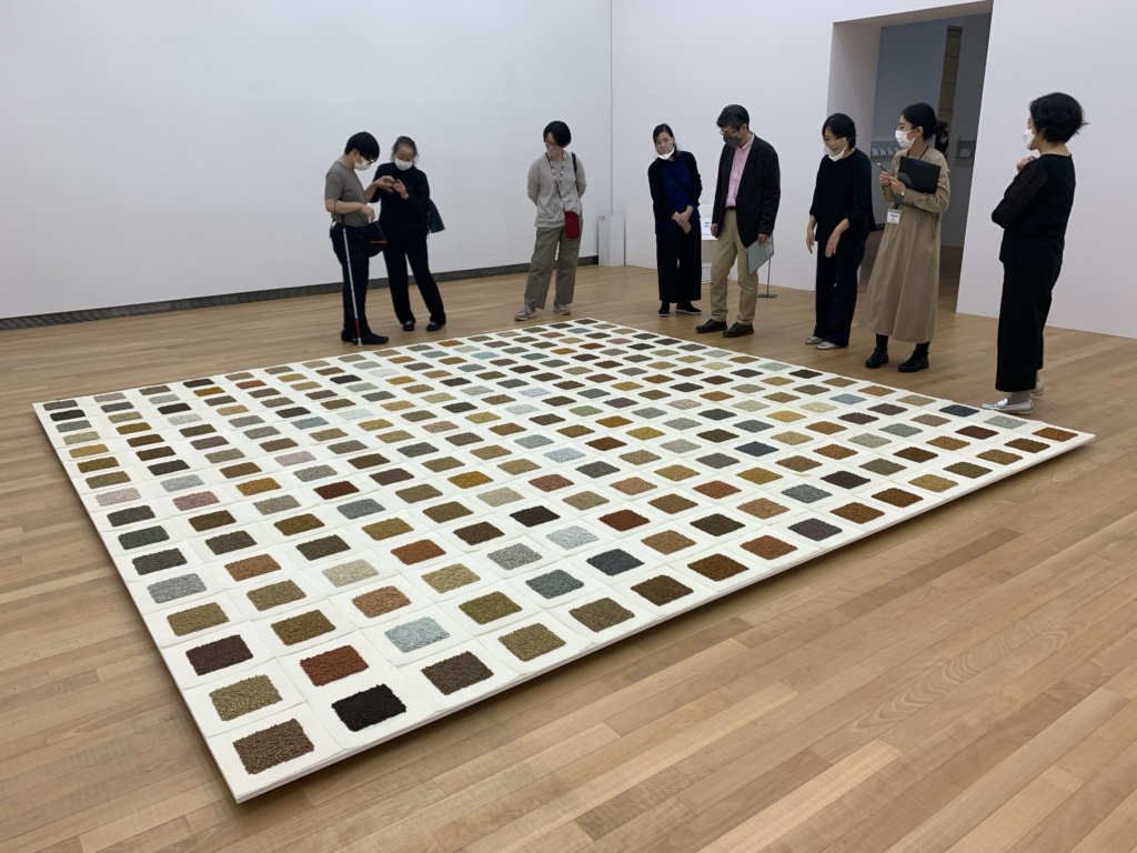 床に置かれた大きな作品を鑑賞している様子が映された写真