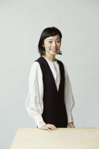白いブラウスにダークなベストを重ね着している女性
