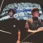 デジタルグラフィックの大きな画面の前で作業を行う二人の男性の写真