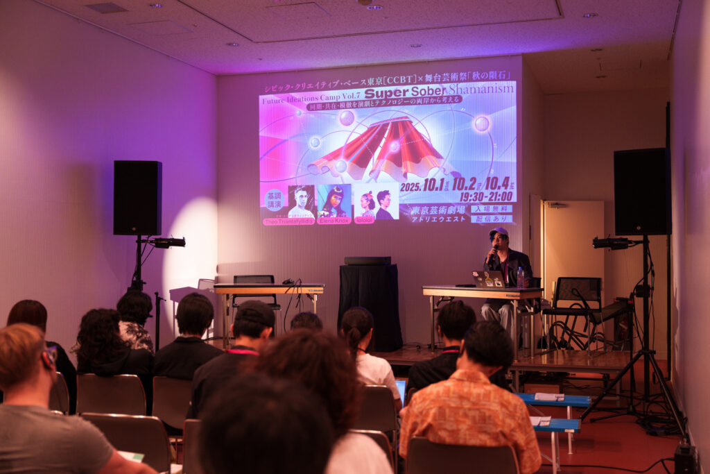 基調講演の一場面の写真。前方のスクリーンにはキャンプのメインビジュアルが映し出されている。壇上ではディレクターのひとりゴッドスコーピオン氏が座り話をしている。