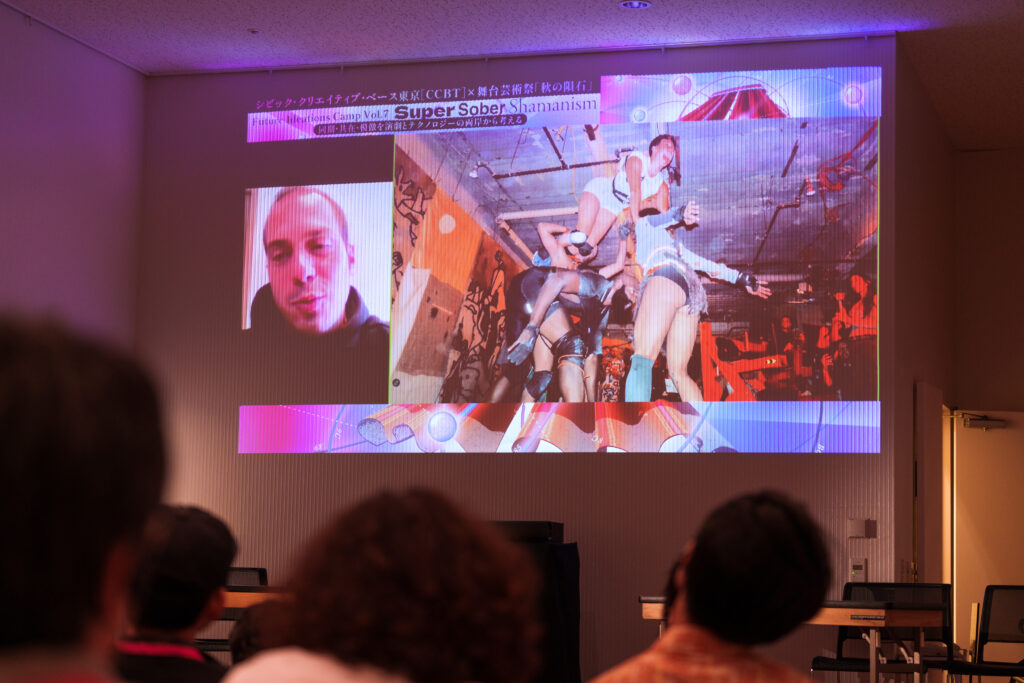 基調講演の一場面の写真。会場のスクリーンに、登壇者であるテオ氏とテオ氏の作品の一場面の映し出されている。